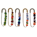 Set of five safety pins with colorful bead embellishments on a white background