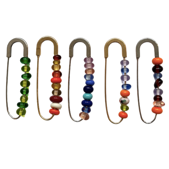 Set of five safety pins with colorful bead embellishments on a white background