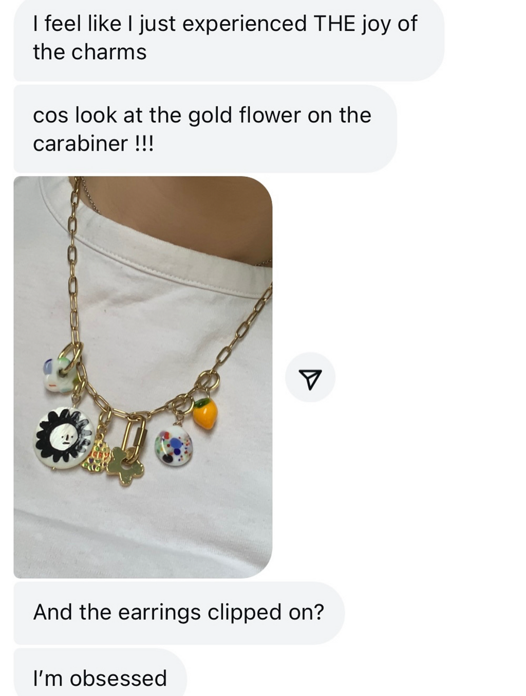 Jewelry with charms on a white background, text expressing admiration for the gold flower charm.
