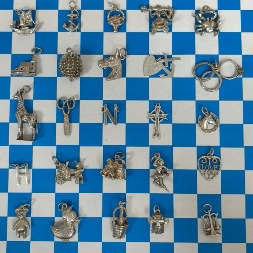 Collection of various silver charms on a blue and white checkered background