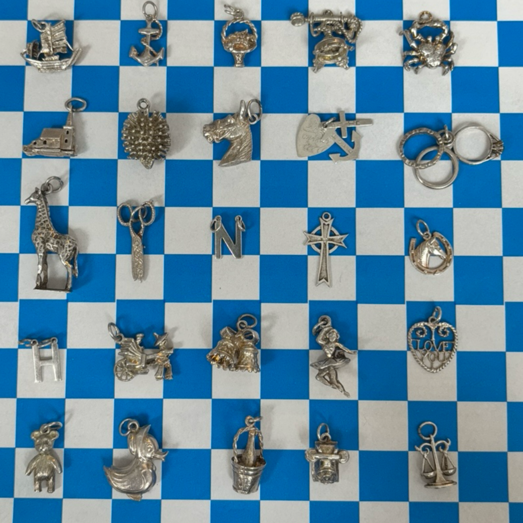 Collection of various silver charms on a blue and white checkered background