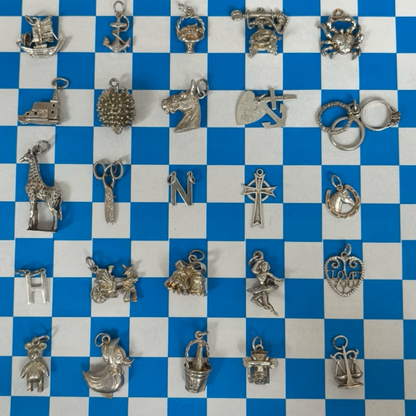 Collection of various silver charms on a blue and white checkered background
