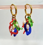 Colorful hoop earrings with gold hooks on a clear stand against a white background