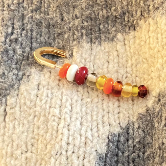 Beaded hook with colorful beads on a textured fabric background