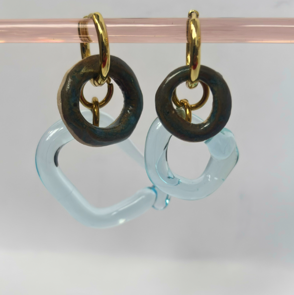 Pair of earrings with gold loops and black and blue circular components on a clear background