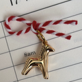 Gold horse charm on red and white string over a calendar page