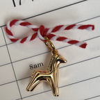 Gold horse charm on red and white string over a calendar page