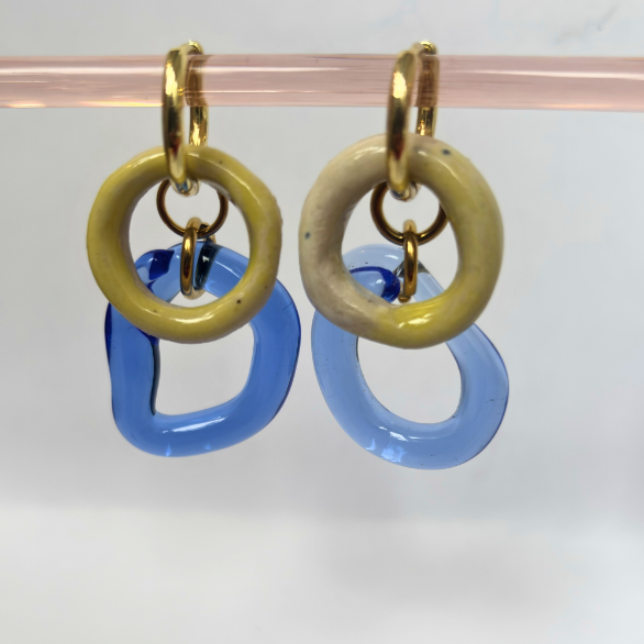 Pair of earrings with gold, beige, and blue circular designs on a white background